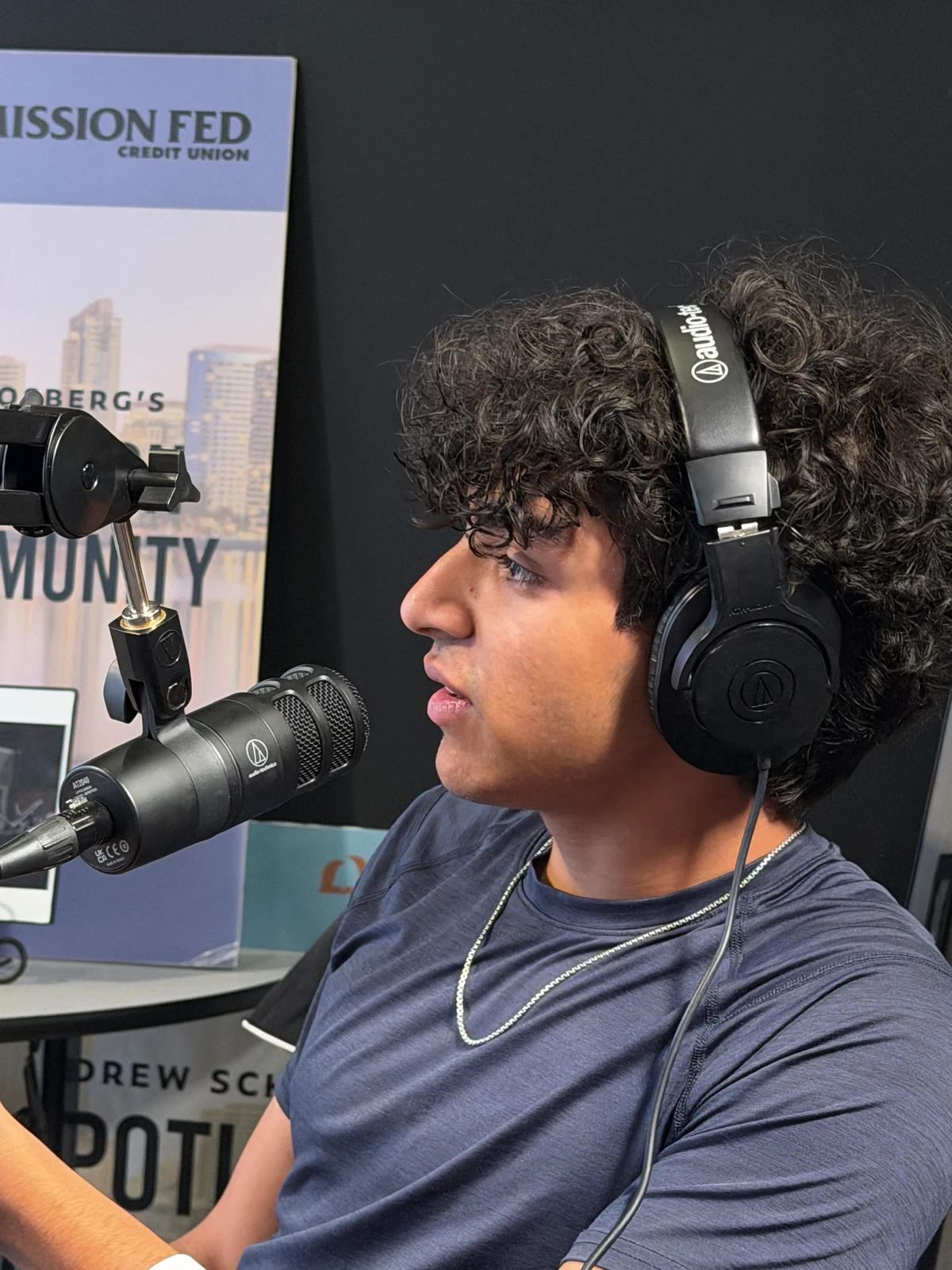 A student in headphones speaking into a studio microphone.